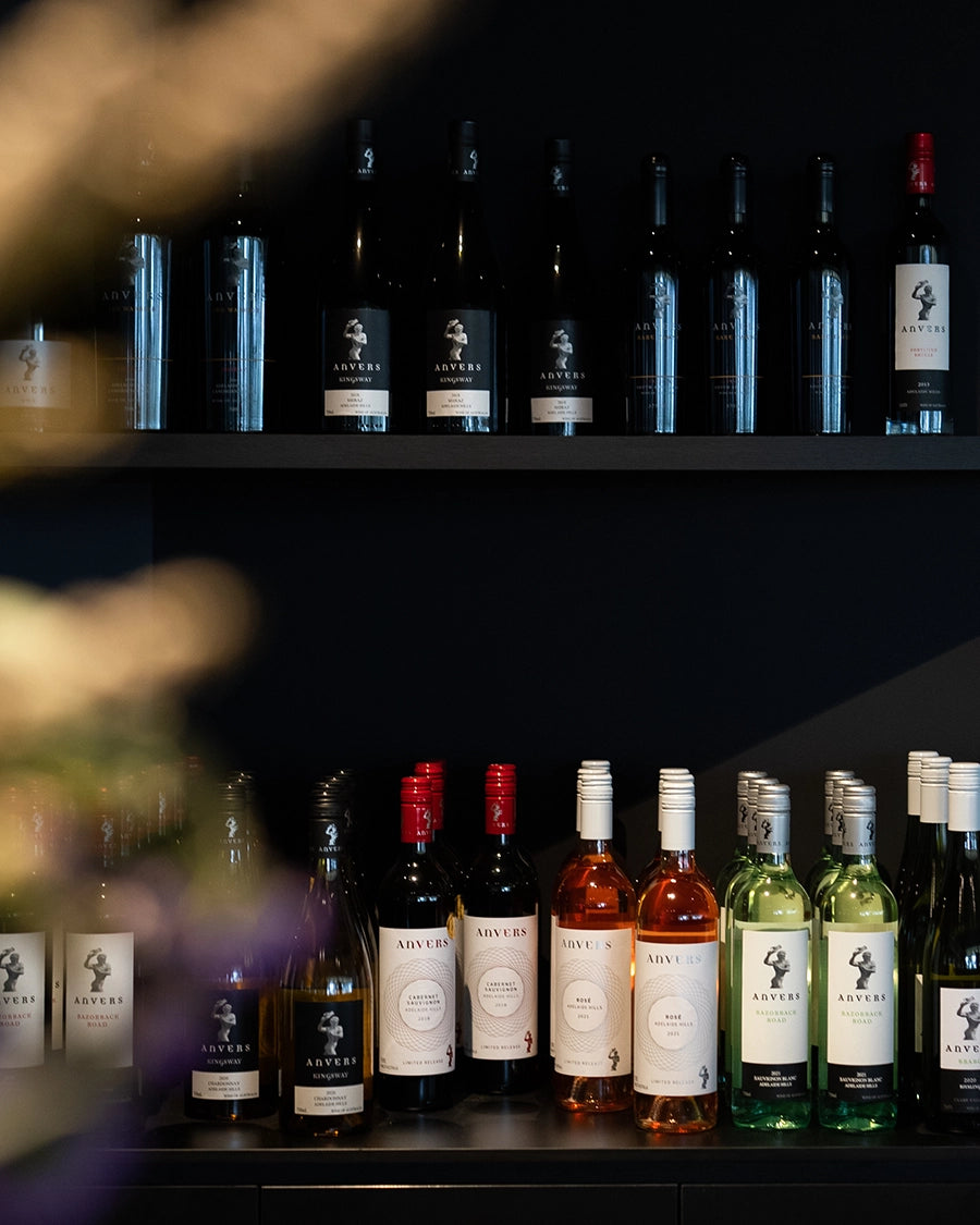 Bottles of Anvers white, red and rose wines stacked on two shelves in the Adelaide Hills
