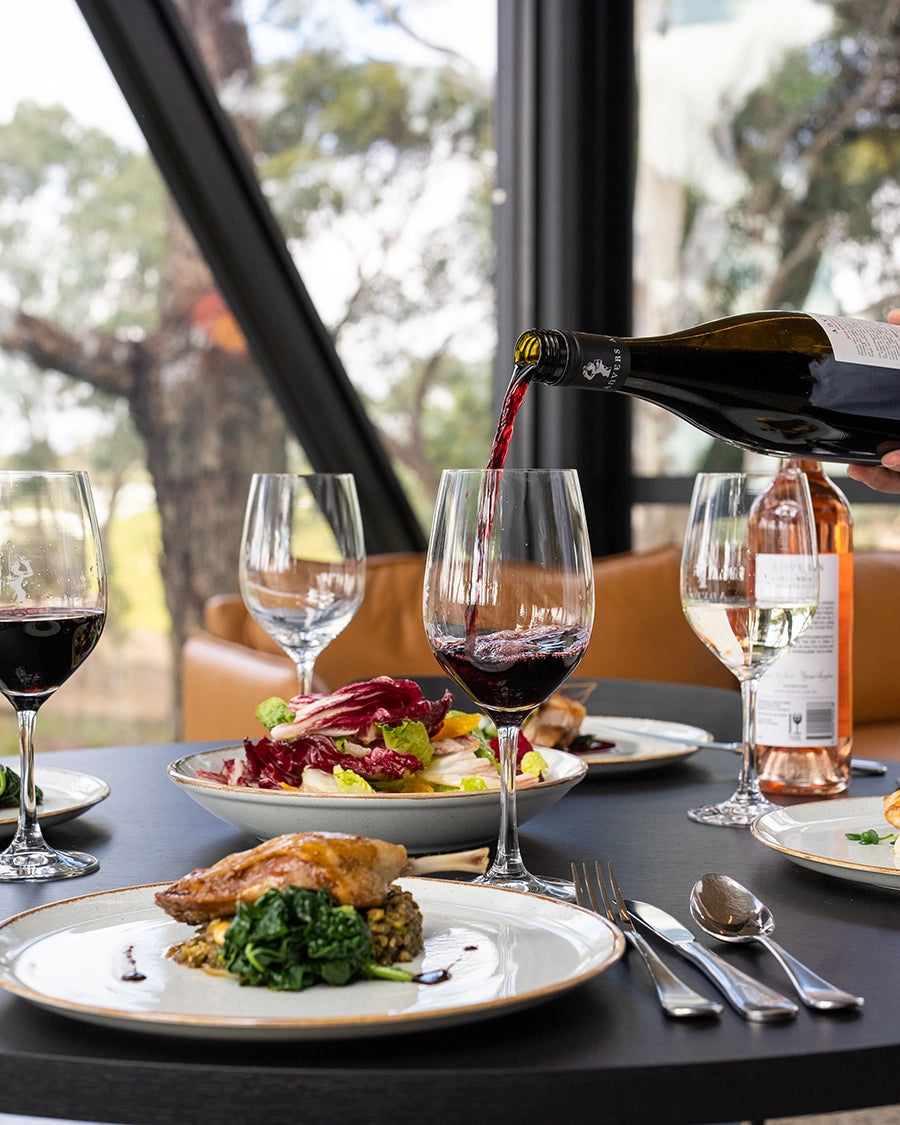 A glass of red wine being poured next to a plate of food at a winery located at Kangarilla in the Adelaide Hills