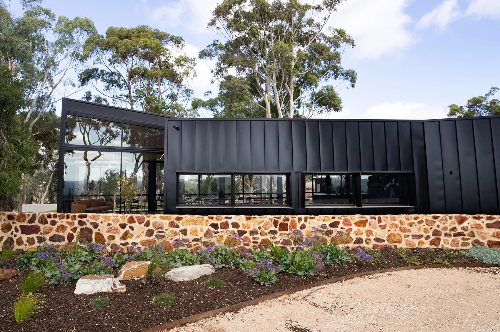 a black colour bond built winery next to a stone wall located at kangarilla in the adelaide hills