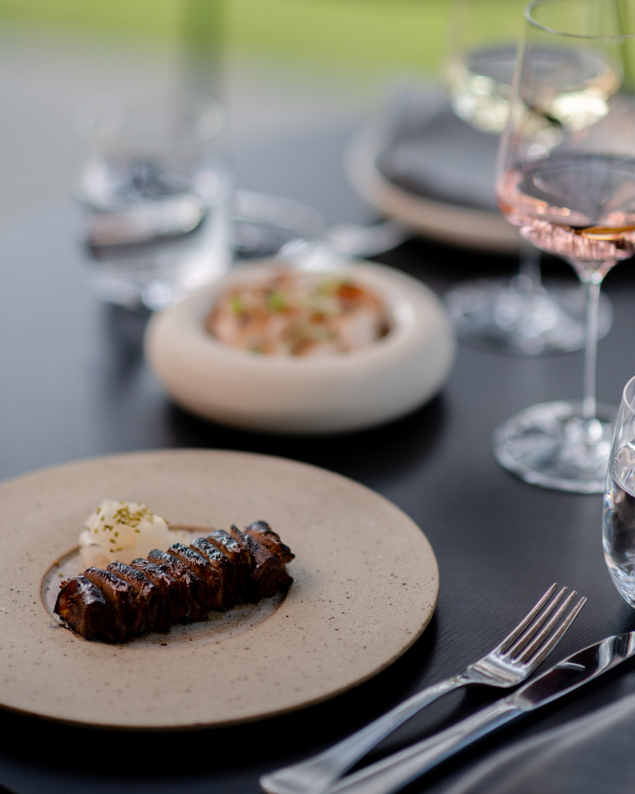 Black table topped with plates of food and wine glasses